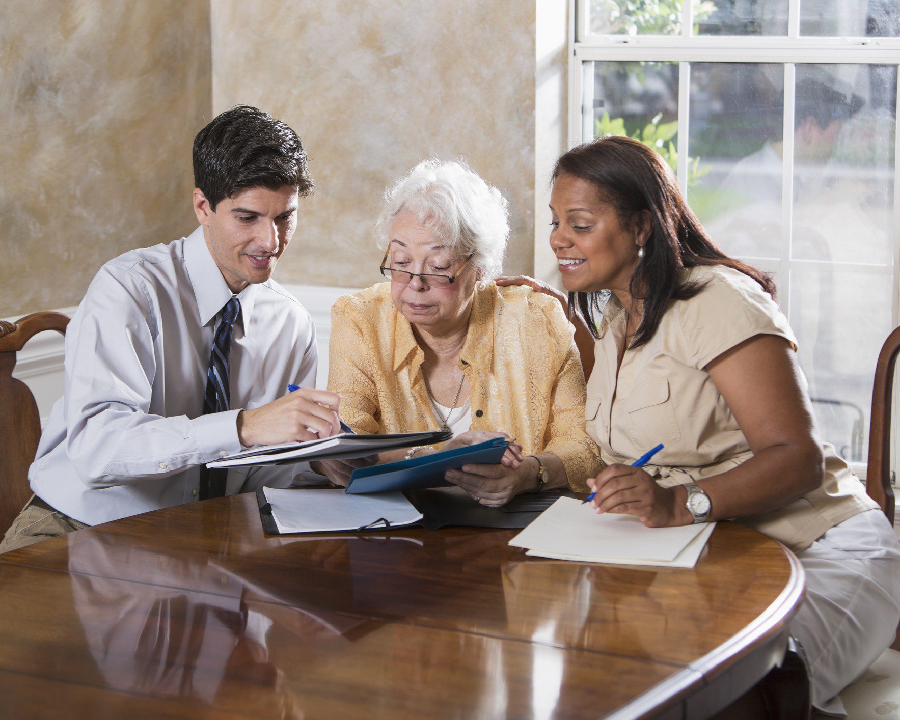 Group discussing paperwork in bright room.