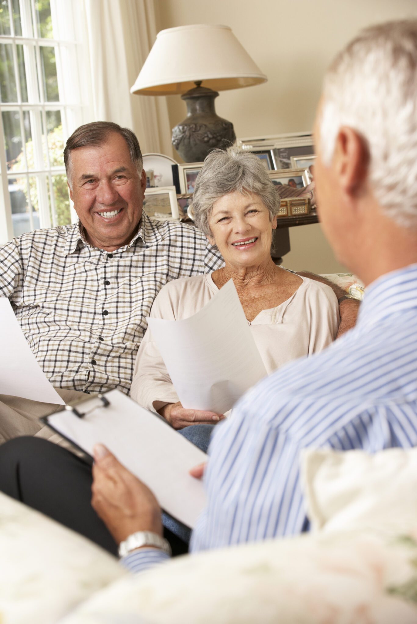 Retired Senior Couple Sitting On Sofa Talking To Financial Advisor